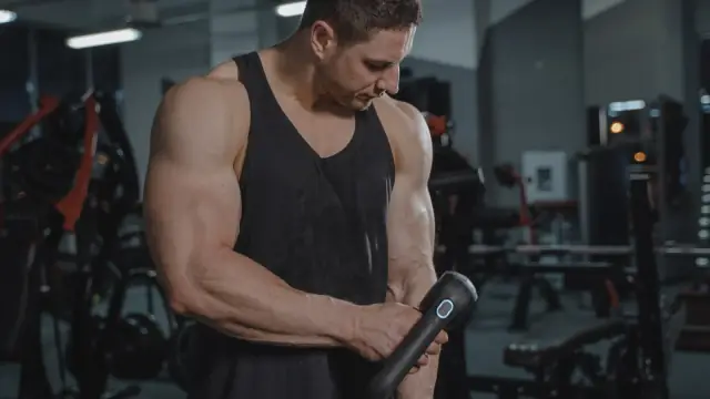Aluno tratando a dor muscular depois do treino com um aparelho de massagem