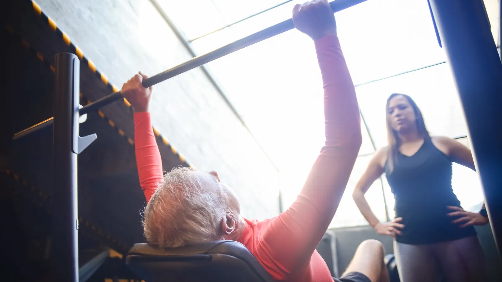 Homem mais velho treinando com acompanhamento em uma academia