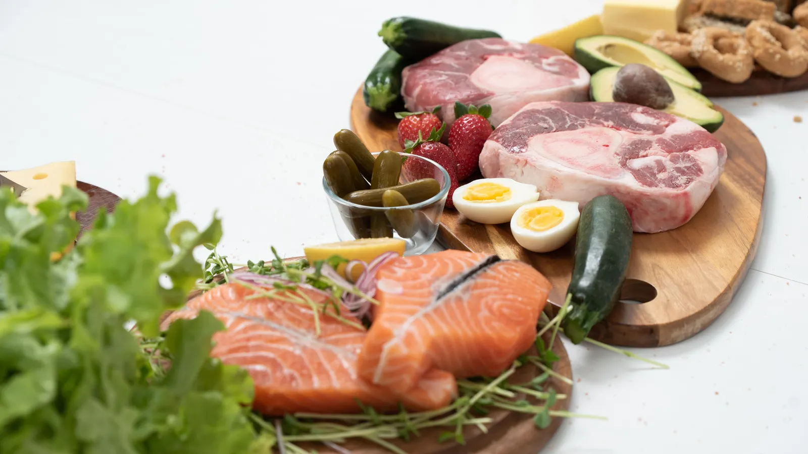 Fontes de proteína sobre tábuas de madeira: salmão, carne, ovo e queijo